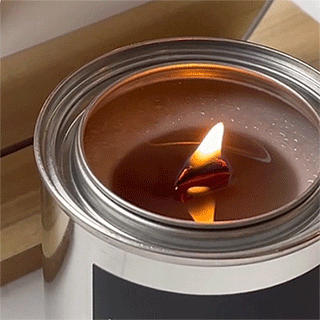 close up of a lit candle flame with pooled wax