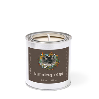 Mala x Merlin Burning Rage candle in a metal tin with a brown label featuring an illustrated cat portrait